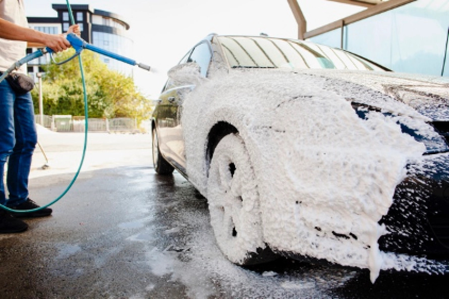 Anciano extiende espuma de jabón de limpieza en su coche en la